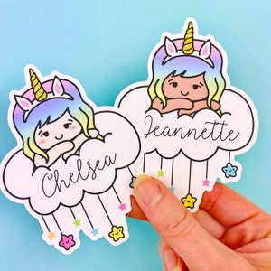 May include: Two colorful unicorn stickers with names "Chelsea" and "Jeannette" on clouds with stars hanging from them.