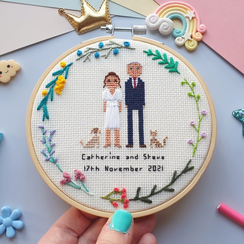 May include: Embroidered hoop art featuring a couple, two dogs, and a floral design border. The text reads "Catherine and Steve 17th November 2021".