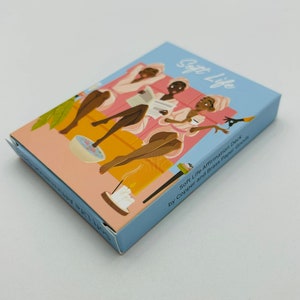May include: A box of Soft Life Affirmation Deck cards by Copper and Grass Paper Goods. The box features an illustration of three women in bathrobes relaxing with candles and a foot bath.