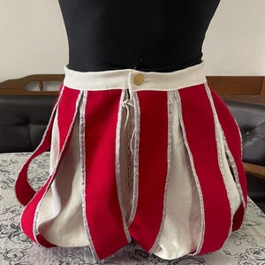 Puede incluir: Pantalones cortos de disfraz rojos y blancos con ribete plateado. Los pantalones cortos tienen una cintura alta con cierre de botón y cordón. Los pantalones cortos están hechos de una tela suave y tienen una forma única y abombada.