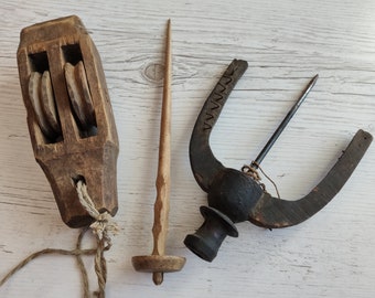 Könnte beinhalten: Drei antike Holz-Spinnwerkzeuge. Das erste ist eine Holzspule mit drei Spulen zum Aufwickeln von Garn. Das zweite ist eine Holzspindel mit einer geschnitzten Spitze. Das dritte ist ein Holzspinnrad mit einem Metallhaken.