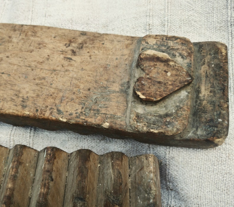 Puede incluir: Un antiguo lavadero de madera con un dise&ntilde;o en forma de coraz&oacute;n tallado en la parte superior. El lavadero est&aacute; hecho de madera toscamente labrada y tiene un aspecto desgastado y r&uacute;stico.