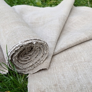 May include: A roll of natural linen fabric, unbleached and woven with a subtle texture. The fabric is rolled up and partially unrolled, revealing the soft, natural color of the linen.