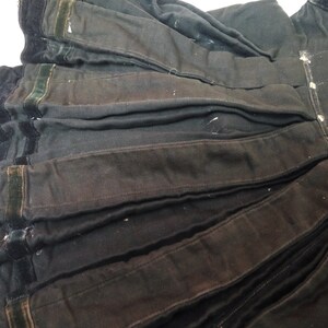 May include: Black skirt with a pleated design and a velvet trim. The skirt has a dark green velvet trim along the bottom edge.