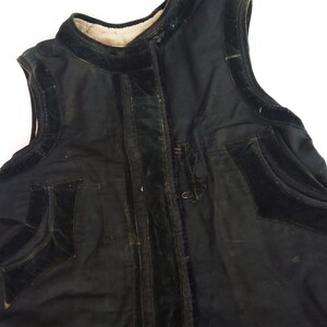 May include: A black sleeveless vest with velvet trim and pockets. The vest has a zipper closure and a stand-up collar.