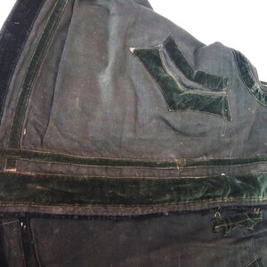 May include: Close-up of the inside of a dark green garment with black velvet trim and a green velvet pocket.