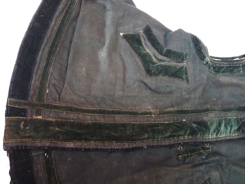 May include: Close-up of the inside of a dark green garment with black velvet trim and a green velvet pocket.