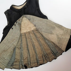 May include: A black velvet dress with a pleated lining. The dress is sleeveless and has a round neckline.