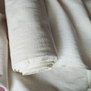 May include: A roll of white fabric, folded and rolled up, with a natural, slightly textured surface.