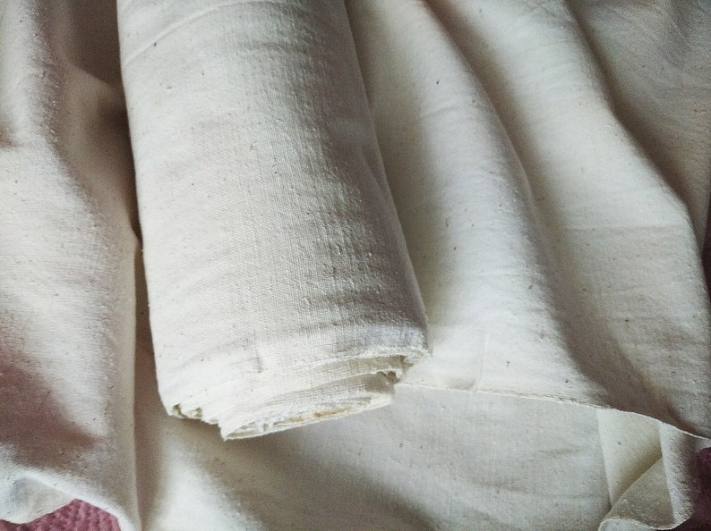 May include: A roll of white fabric, folded and rolled up, with a natural, slightly textured surface.
