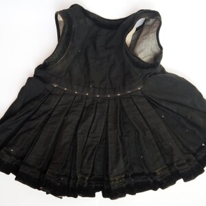 May include: A black sleeveless dress with a pleated skirt and velvet trim. The dress is made of a soft, lightweight fabric.