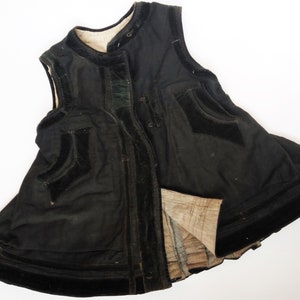 May include: A black sleeveless garment with a velvet trim and a button closure. The garment has a flared skirt and a lining.