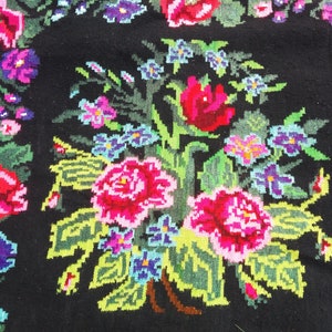 May include: A black rug with a floral pattern. The flowers are red, pink, blue, and green. The rug is made of wool and has a traditional design.