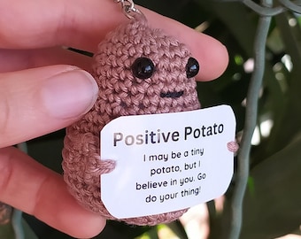 Peut inclure: Un porte-clés en forme de pomme de terre crocheté avec un message qui dit "Positive Potato I may be a tiny potato, but I believe in you. Go do your thing!"