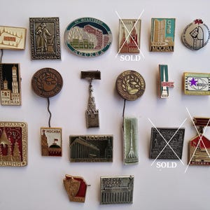 Puede incluir: Una colección de pines y insignias vintage con temática de Moscú. Los pines presentan varios diseños, incluyendo edificios, monumentos y texto en ruso. La paleta de colores incluye oro, rojo, verde y plata. Algunos pines tienen un pasador.