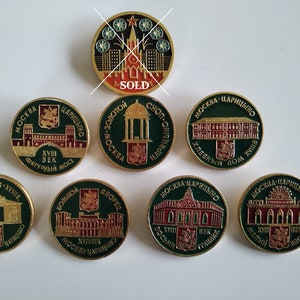 May include: A collection of eight round, gold-colored pins with green and red enamel. Each pin features a different building from Moscow, Russia, with the text "Moscow- Tsaritsyno" and the year "XVIII век" (18th century) on each pin.