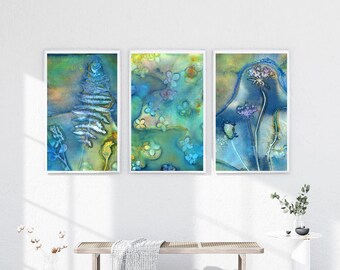 Può includere: Tre stampe artistiche ad acquerello incorniciate con disegni botanici. L'opera presenta una felce, motivi floreali e fiori selvatici nelle tonalità del blu, verde e giallo. Le stampe sono esposte su una parete bianca sopra una panca di legno.
