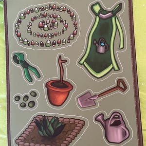 Pode incluir: Uma folha de adesivos com ilustrações com tema de jardinagem. Inclui um avental verde com um regador, um regador, uma pá, uma planta em vaso, um canteiro, um círculo de cogumelos e tesouras de poda. O nome do artista, @starkittyarts, está na parte inferior.