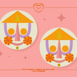 May include: Two colorful, whimsical clock faces with a smiling expression. The clock faces are in a circle with a yellow triangle on top, purple arms, orange eyes, and orange pom-poms on the sides. The text "It's a small world clock face - 3 in. sticker" is below the clock faces.