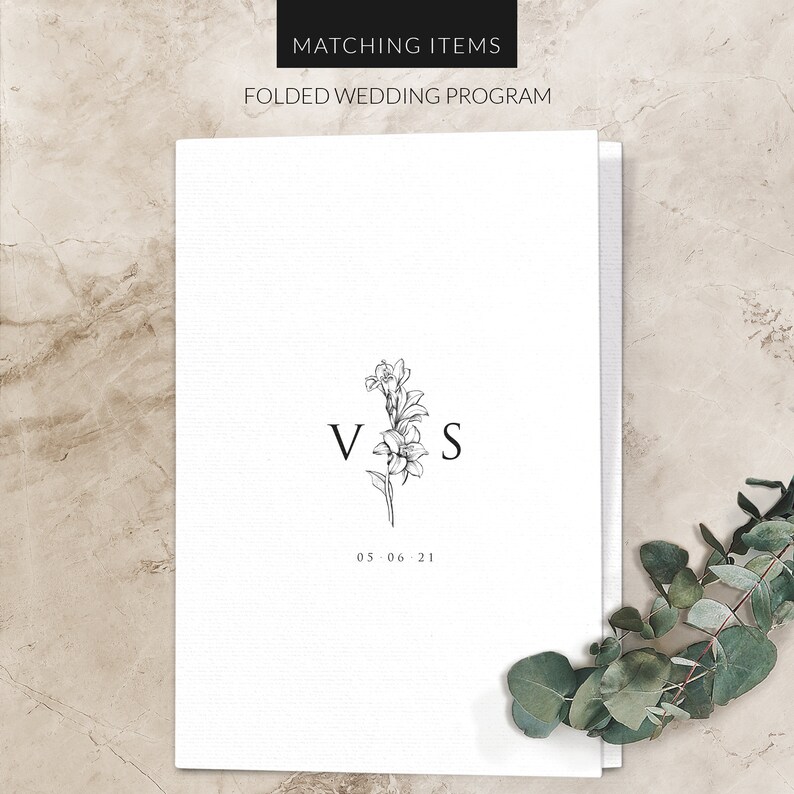 May include: A white folded wedding program with a black floral design and the initials "V & S" and the date "05.06.21".