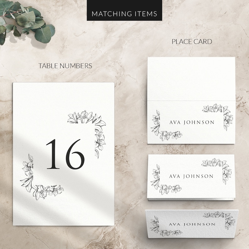 May include: White wedding table number card with a black floral border and the number 16 in black font. Matching place cards with the name "AVA JOHNSON" in black font are also shown.