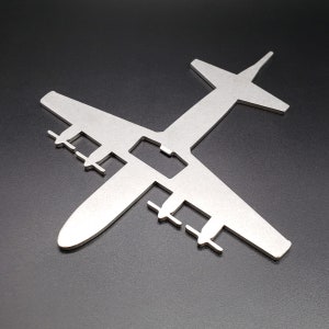 May include: A silver metal cutout of a plane. The plane is in a silhouette style and has a detailed design.