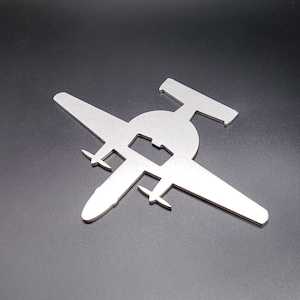 May include: A silver metal airplane bottle opener. The airplane is in silhouette and has a bottle opener in the center of the fuselage.