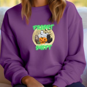 May include: Purple sweatshirt with a green graphic of a full moon, a ghost, an owl, a black cat, and a jack-o-lantern. The text "FRIGHT SHIFT" is written in green below the moon.