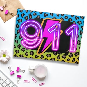 May include: A black and yellow leopard print makeup bag with a neon pink and blue lightning bolt and the number 911 in neon pink.