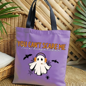 May include: Purple tote bag with black handles and a Halloween design. The bag features a ghost wearing headphones with the text "You can't scare me I'm a dispatcher".