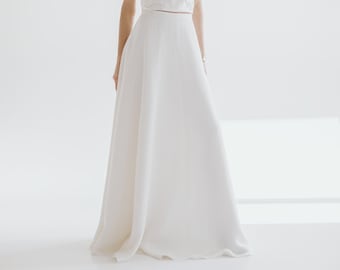 May include: A white strapless top with a gathered bodice and a matching white maxi skirt. The skirt has a simple, flowing silhouette.