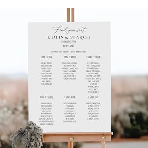 May include: A wedding seating chart on an easel. The sign reads "Find your seat" and lists the names of the couple, Colin & Sharon, and the date, June 2nd, 2026. Names are organized by table number.