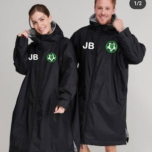 Puede incluir: Dos chaquetas negras con capucha y cierre de cremallera. Las chaquetas tienen un logotipo blanco con un balón de fútbol verde y las iniciales "JB" en la parte delantera.