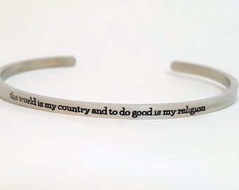May include: A silver bangle bracelet with the inscription "the world is my country and to do good is my religion".