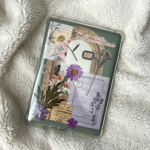 May include: A clear, rectangular phone case with a collage of pressed flowers, vintage paper, and ephemera. The design includes purple and yellow flowers, botanical elements, and handwritten script. The case has a green border.