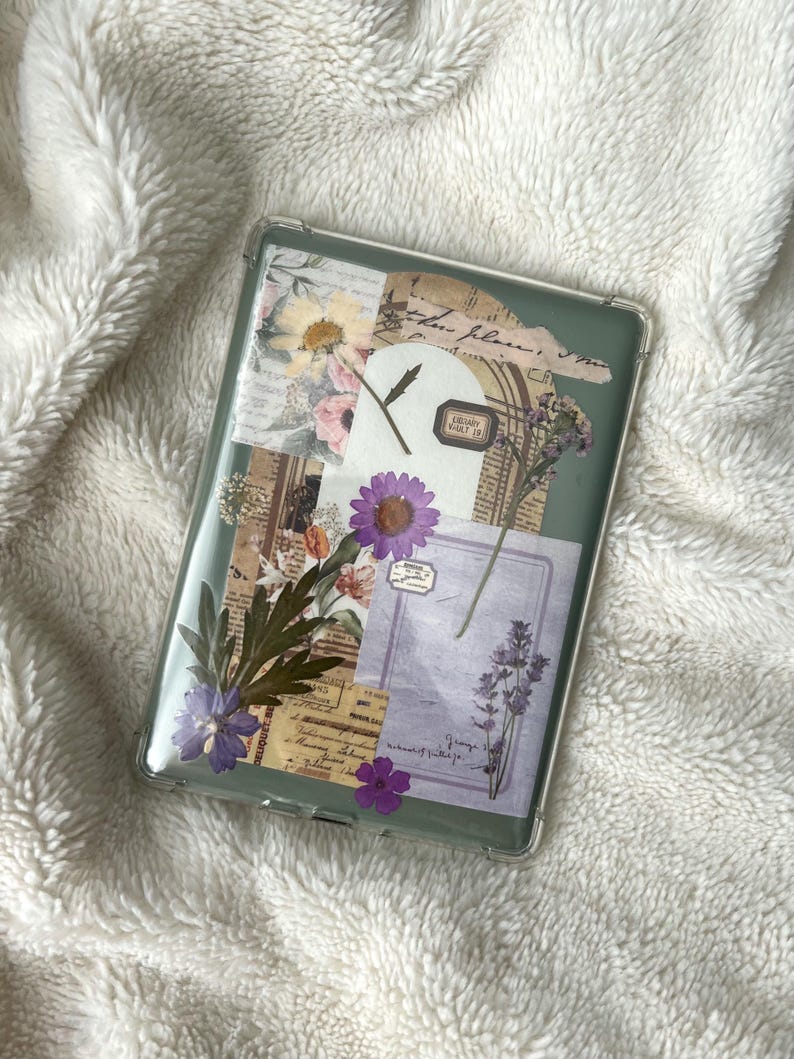 May include: A clear, rectangular phone case with a collage of pressed flowers, vintage paper, and ephemera. The design includes purple and yellow flowers, botanical elements, and handwritten script. The case has a green border.