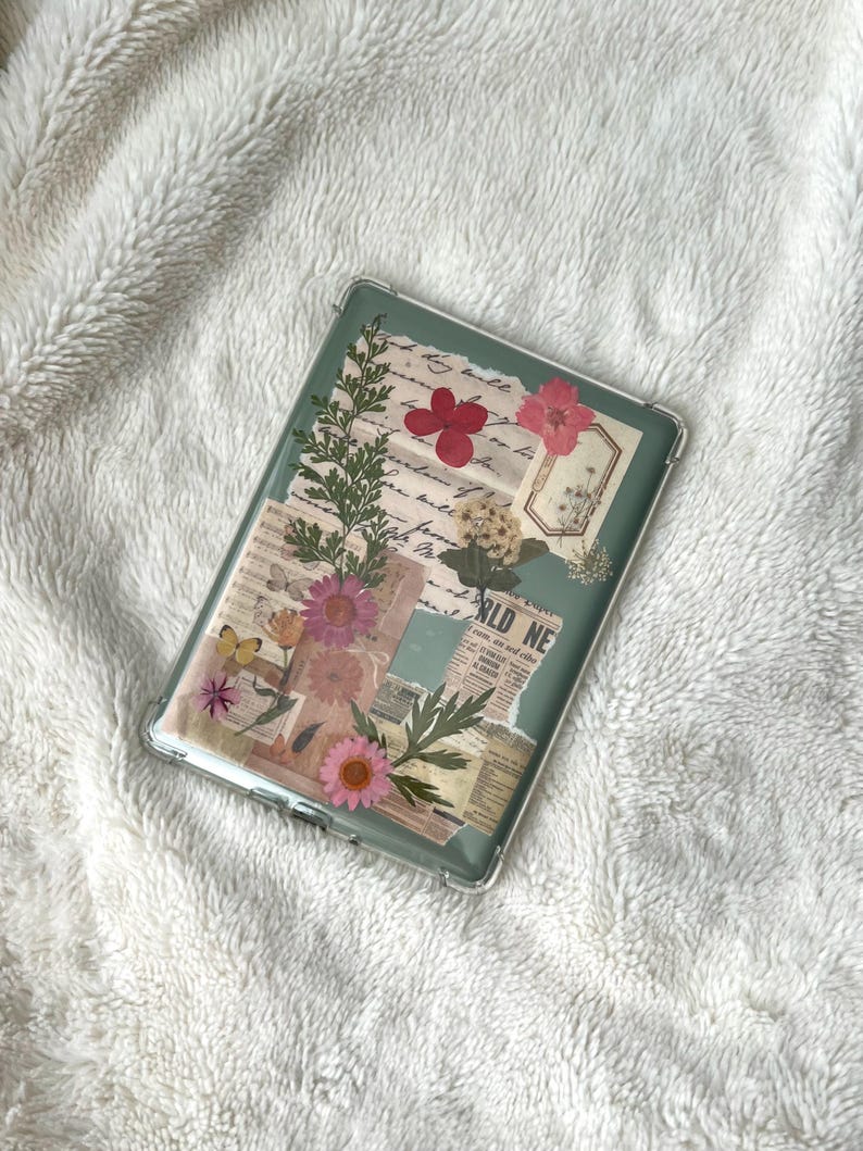 May include: Clear phone case with a collage design featuring pressed flowers, newspaper clippings, and botanical elements. The case has a green background and a variety of pink and yellow flowers. The text "WORLD NEWS" is visible.