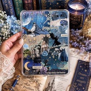May include: A clear phone case with a collage design featuring a mountain, stars, and text that reads "feyre, darling" and "high lord." The case is surrounded by books, flowers, and a candle.