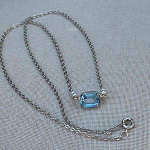 Vintage Avon signed prong set emerald cut ice blue faux topaz glass stone pendant with faux pearls on a silver tone 18” chain