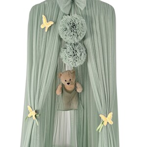Puede incluir: Una carpa de tul verde con una corona dorada en la parte superior. La carpa tiene un lazo en la parte superior y est&aacute; decorada con mariposas amarillas y pompones verdes. Un osito de peluche cuelga del interior de la carpa.