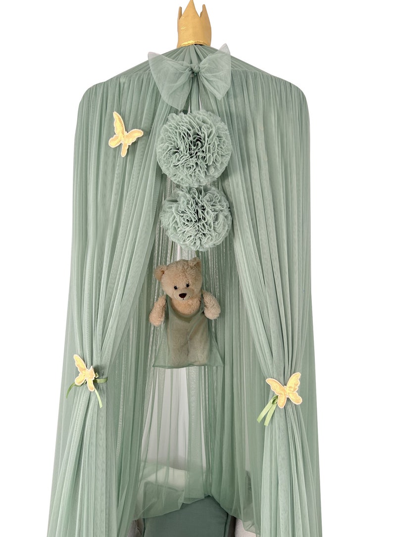 Puede incluir: Una carpa de tul verde con una corona dorada en la parte superior. La carpa tiene un lazo en la parte superior y est&aacute; decorada con mariposas amarillas y pompones verdes. Un osito de peluche cuelga del interior de la carpa.