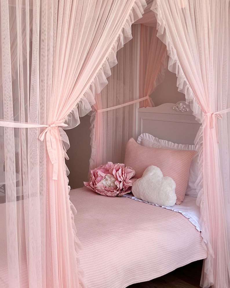 May include: A pink canopy bed with a white cloud-shaped pillow and a pink flower pillow. The bed is covered in a pink striped bedspread.