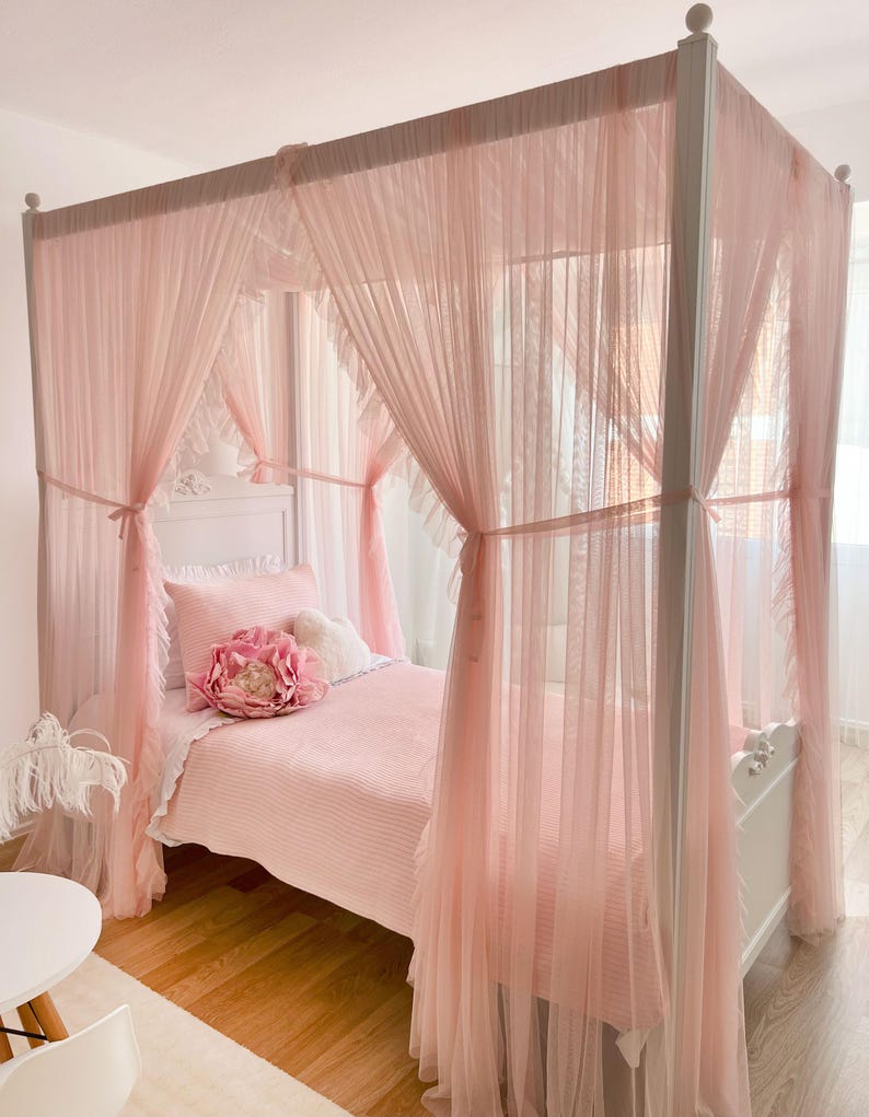 May include: A white canopy bed with a pink ruffled canopy and a pink striped bedspread. A large pink flower pillow is on the bed.