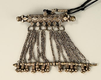 Peut inclure: Un pendentif en argent avec un haut rectangulaire long et orné et plusieurs chaînes avec de petites perles en argent au bas.