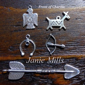 May include: Five silver charms, including a bird, a deer, a horseshoe, a bow and arrow, and an arrow. The charms are on a wooden surface with the text "Front of Charms" and "Janie Mills" visible.