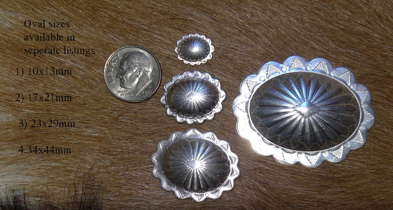 May include: Four silver oval-shaped conchos with a sunburst design. The conchos are different sizes, with the largest measuring 4.34 inches by 4.44 inches. The text "Oval sizes available in seperate listings" is visible in the image. 1) 10x13mm 2) 17x21mm 3) 23x29mm 4.34x44mm