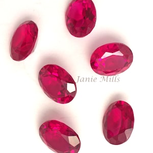Pode incluir: Seis gemas ovaladas de cor vermelha brilhante sobre um fundo branco.  Janie Mills está escrito em texto preto sobre o fundo branco.