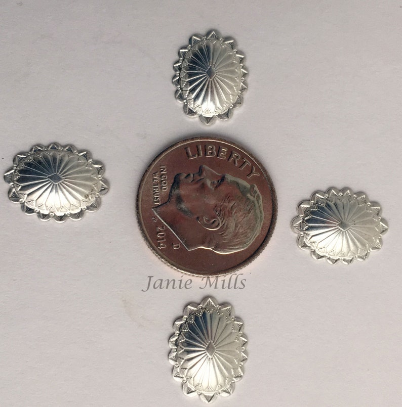 May include: Four silver-toned metal conchos with a sunburst design. The conchos are approximately the size of a US dime.