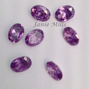 May include: Seven oval-shaped, purple gemstones with a faceted finish.