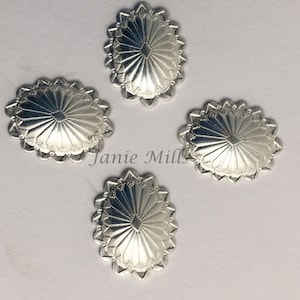 May include: Four silver-toned metal conchos with a sunburst design. Each concho has a scalloped edge.